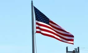 United States flag waving on a pole with a clear blue sky background in Florida.