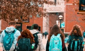 A group of college students with backpacks walking together outdoors on campus.