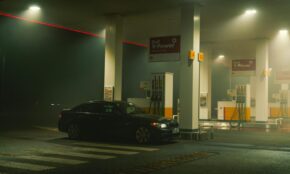 A BMW sports car parked at a Shell gas station at night, featuring bright lights and an urban setting.