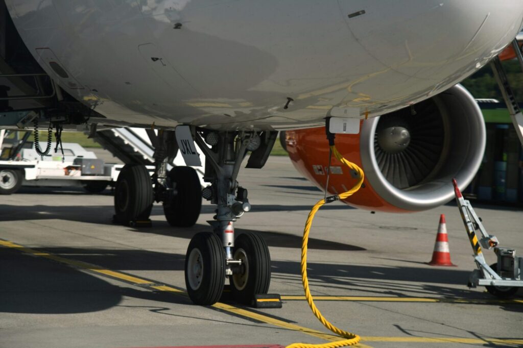 Detailed view of airplane landing gear and engine on tarmac in Geneva, Switzerland.