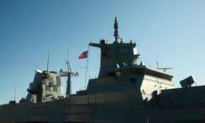 A Norwegian navy frigate with a national flag in daylight.