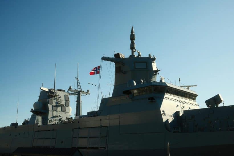A Norwegian navy frigate with a national flag in daylight.