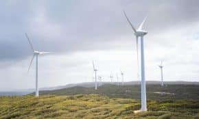 Majestic wind turbines harnessing energy in a vast green landscape under cloudy skies.
