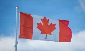 A vibrant Canadian flag waving in the breeze against a bright blue sky, symbolizing national pride.
