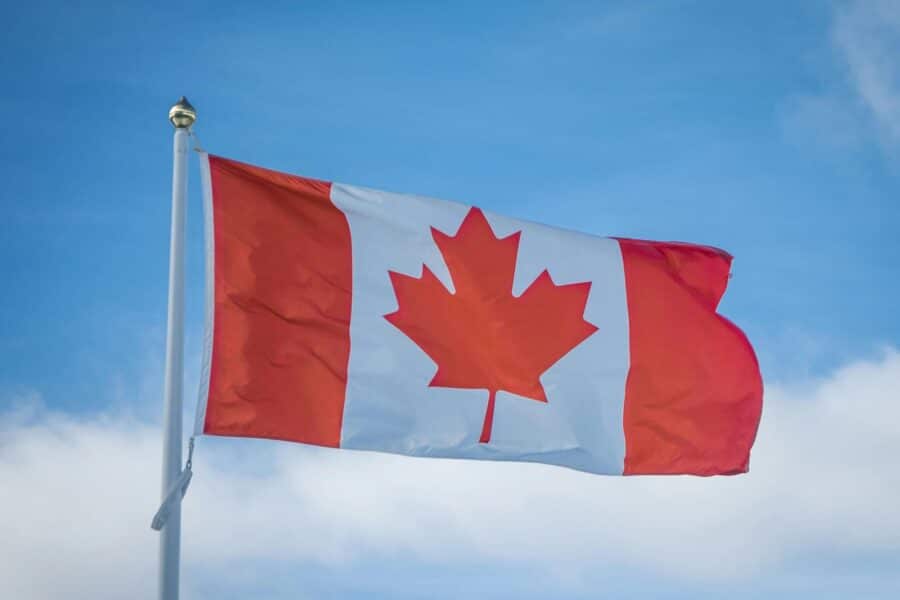A vibrant Canadian flag waving in the breeze against a bright blue sky, symbolizing national pride.