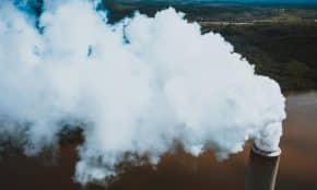 From above of thick fume stream coming out of masonry smokestack at power plant