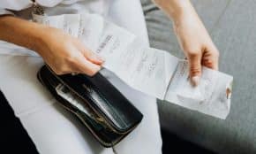 Close-up of a woman's hands managing multiple receipts taken from a black wallet.