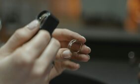 Close-up of a jeweler's hands holding a diamond ring and magnifying glass.