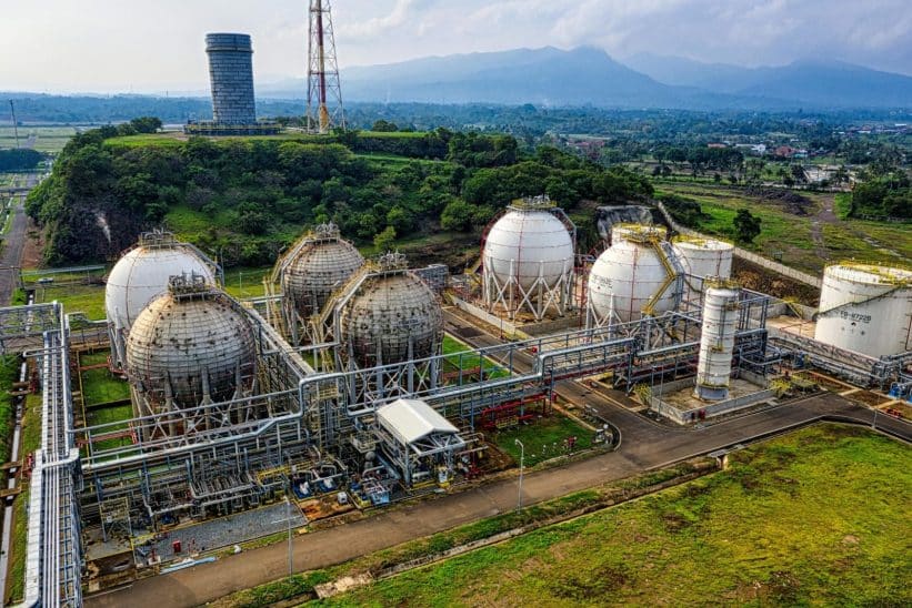 Aerial shot of a power plant with storage tanks in lush Banten, Indonesia offers an impressive scale.