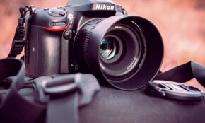 Nikon DSLR camera with lens cap on backpack, showcasing photography gear in an outdoor setting.