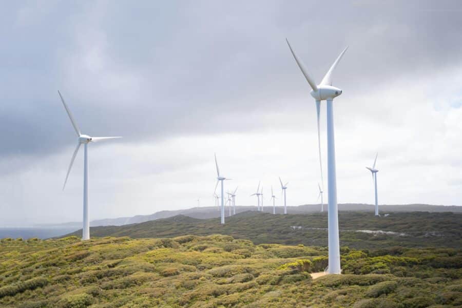 Majestic wind turbines harnessing energy in a vast green landscape under cloudy skies.