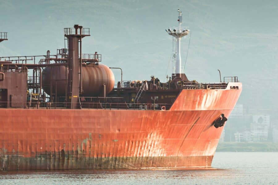 Large red cargo ship sails on the water