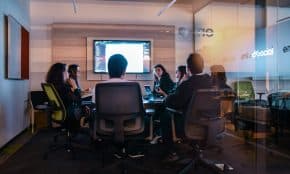 a group of people sitting in chairs in front of a projector screen