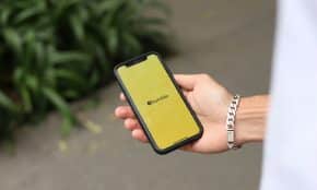 a person holding a yellow cell phone in their hand