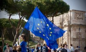 a young girl holding a european flag in front of a crowd of people