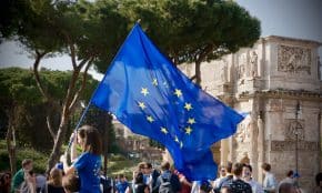 a young girl holding a european flag in front of a crowd of people