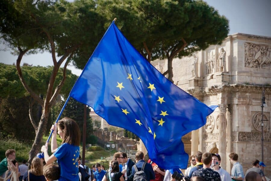 a young girl holding a european flag in front of a crowd of people