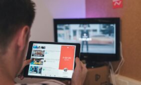 man browsing tablet sitting in front of TV