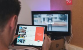 man browsing tablet sitting in front of TV