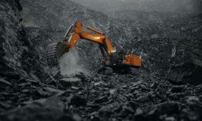 An orange excavator digging through a rocky area