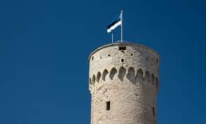 brown concrete tower with blue, black, and white flag on top