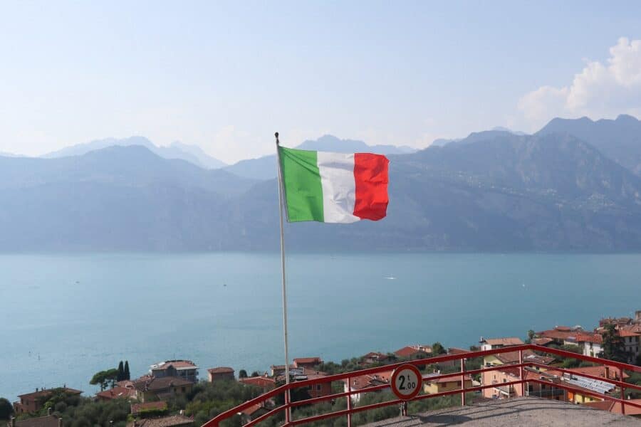 a flag flying on top of a hill next to a body of water