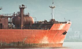Large red cargo ship sails on the water
