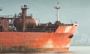 Large red cargo ship sails on the water