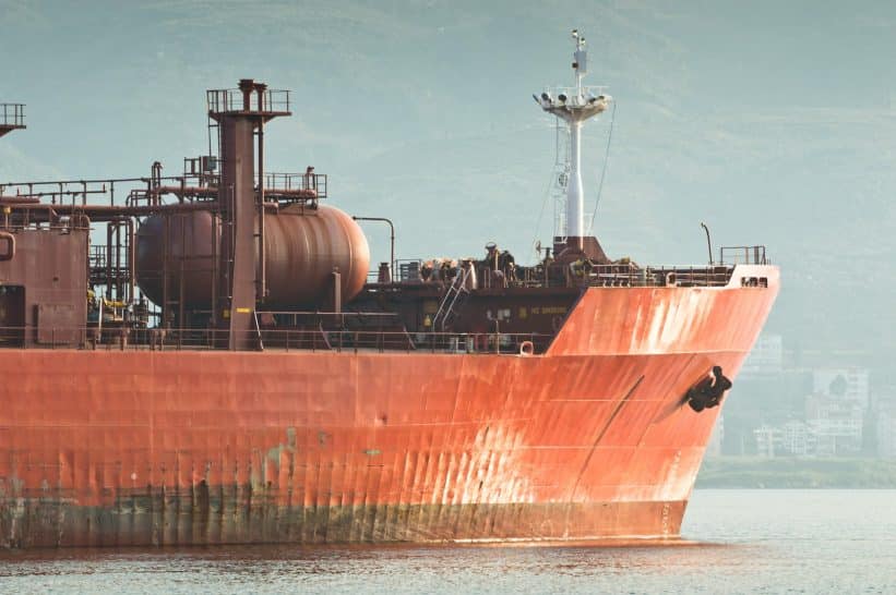 Large red cargo ship sails on the water