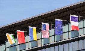 Flags of various nations fly on building.