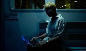 A man sitting on a train using a laptop computer