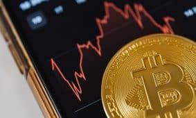 Bitcoin monetos ant tamsaus fono, simbolizuojančios kriptovaliutų rinką po JAV ir Irano konflikto