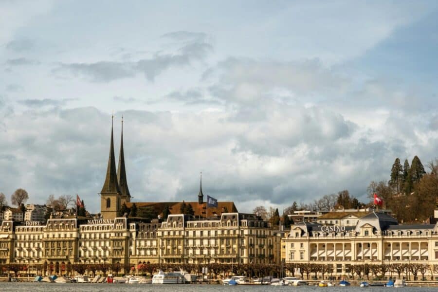 View of Lucerne's picturesque cityscape featuring iconic architecture, lake, and Casino Lucerne under a cloudy sky.